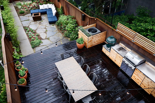Outdoor deck flooring material is dark wood with backyard kitchen